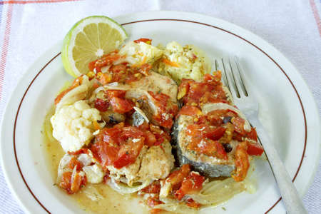 Baked fish with vegetables on plateの写真素材