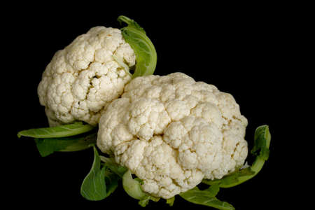 Cauliflower with green leaves in isolated over black backgroundの写真素材