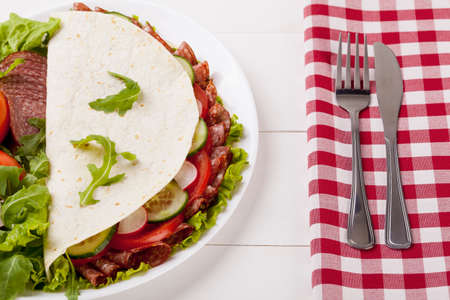 Italian Piadina Romagnola with salami and vegetables on white woodboardの写真素材