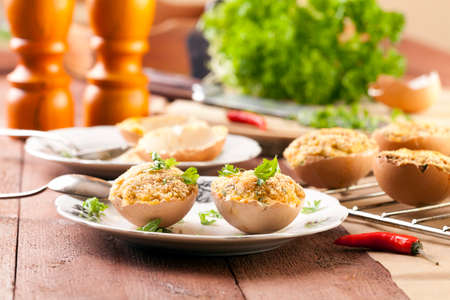 Baked eggs, stuffed with ham and parsley, served in the eggshell - focus on eggの写真素材