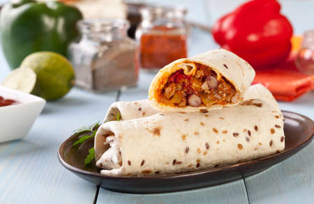 burritos wraps with meat beans and vegetables on blue wood boardの写真素材