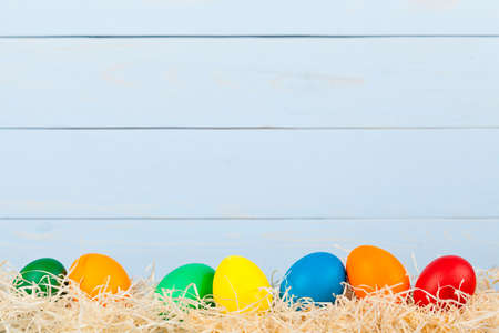 easter backgroud from colored eggs on blue woodboardの写真素材