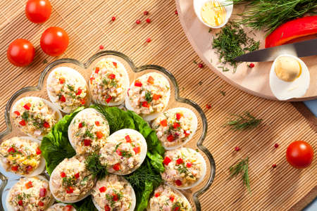 stuffed eggs with ham, red pepper and dill on plateの写真素材