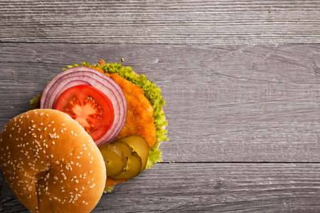 Home made chicken burger with lettuce, tomato and onion on wooden boardの写真素材