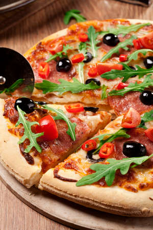Pizza peperoni on plate with black olives, rocket and mozzarella cheeseの写真素材