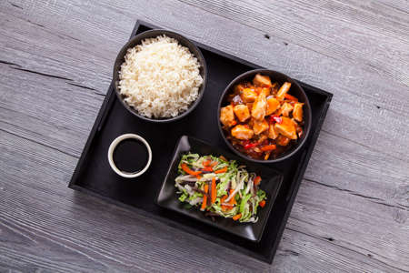 Chinese chicken sweet and sour sauce, served with rice and vegetables on woodboardの写真素材