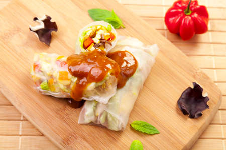 Portion of spring rolls on a bamboo board with dipping sauce