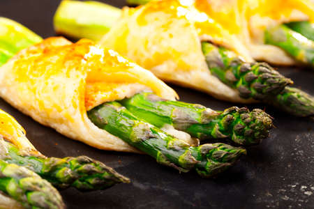 Asparagus baked in puff pastry served on black plateの写真素材