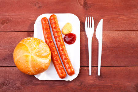 Roasted sausage with bread served on a paper tray - wood boardの写真素材