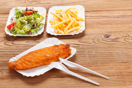 Fried fish and chips on a paper tray - Natural wooden background