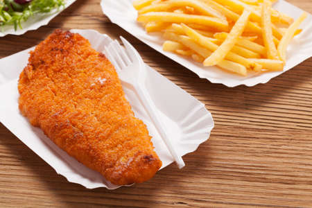 Fried fish and chips on a paper tray - Natural wooden backgroundの写真素材
