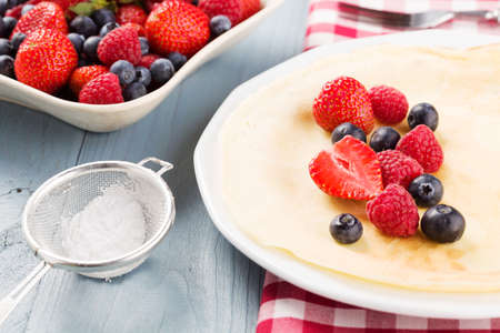 Delicious pancakes with raspberries, blueberries and strawberries. Sprinkled with powdered sugar.の写真素材