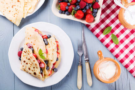Delicious pancakes with raspberries, blueberries and strawberries. Sprinkled with powdered sugar.の写真素材
