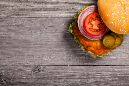 Home made chicken burger with lettuce, tomato and onion on wooden boardの写真素材