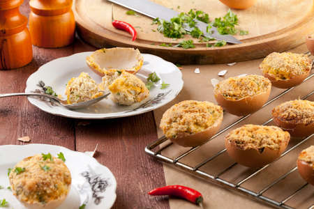 Baked eggs, stuffed with ham and parsley, served in the eggshellの写真素材