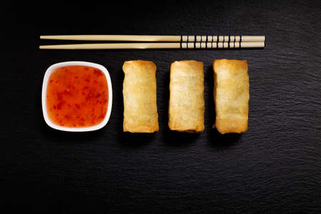 Baked spring rolls with deep, rice and vegetables, on a black plateの写真素材