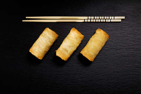 Baked spring rolls with vegetables, on a black plateの写真素材