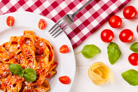 Pasta tagiatelle with tomato on white woodboardの写真素材