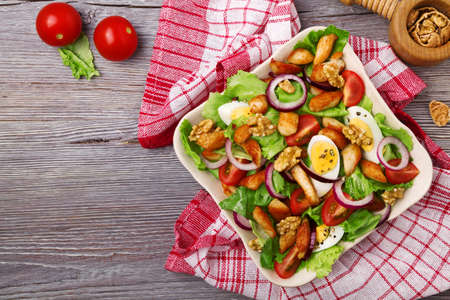 Delicious salad with chicken, nuts, egg and vegetables.の写真素材