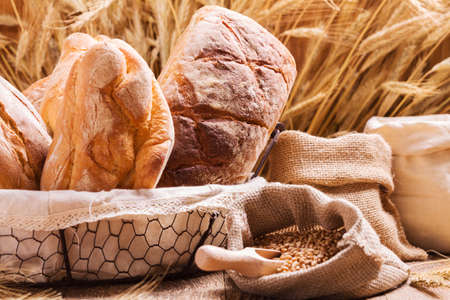 Composition of fresh bread, cereals and grains on wooden board.