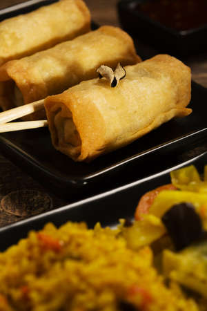 Baked spring rolls with vegetables on a black plate.