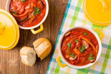 Delicious letcho with fresh vegetables, served in a yellow pot with the fresh bun.の写真素材