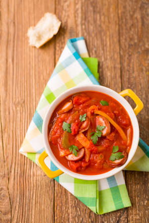 Delicious letcho with fresh vegetables, served in a yellow pot with the fresh bun.の写真素材