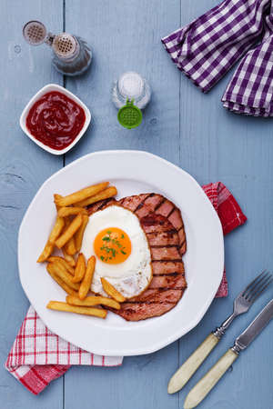 English breakfast with grilled ham, fried egg and french fries.の写真素材