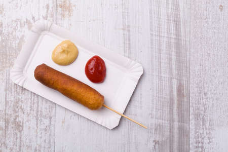 Corn dog. Sausage baked in corn dough served with ketchup and mustard on a paper tray.の写真素材