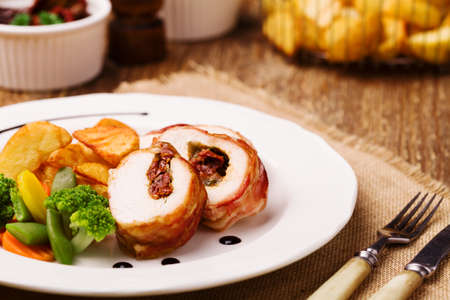 Delicious chicken rolls with dried tomatoes and mozzarella, served with vegetables and roasted potatoes.の写真素材