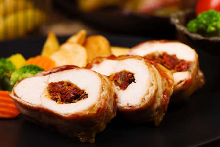 Delicious chicken rolls with dried tomatoes and mozzarella, served with vegetables and roasted potatoes.の写真素材