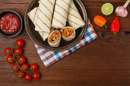 Burritos wraps with meat, beans and vegetables on wooden boardの写真素材