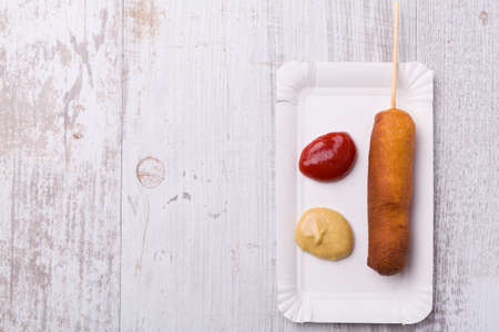 Corn dog. Sausage baked in corn dough served with ketchup and mustard on a paper tray.の写真素材