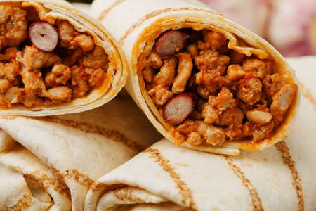 Burritos wraps with meat, beans and vegetables on wooden boardの写真素材