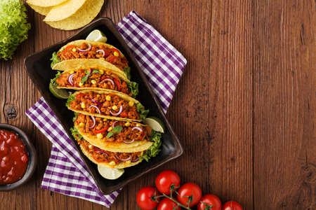 Few portion of tacos with meat and vegetables on wooden boardの写真素材