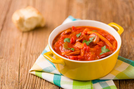 Delicious letcho with fresh vegetables, served in a yellow pot with the fresh bun.の写真素材