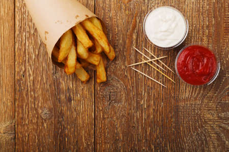 Serving Belgian fries served in a paper tube, with or without a dip. On a wooden table.の写真素材