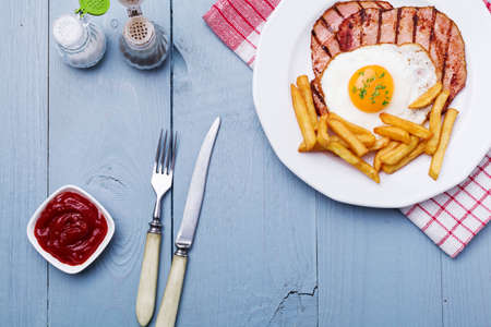 English breakfast with grilled ham, fried egg and french fries.の写真素材