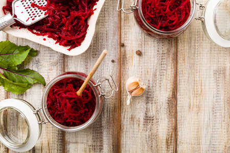 Grated beetroot marinated in jars. Wooden background. Top view.の写真素材