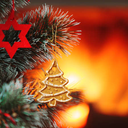Christmas tree with gingerbread, suspended on a twig Christmas tree. Blazing fireplace in the background.の写真素材