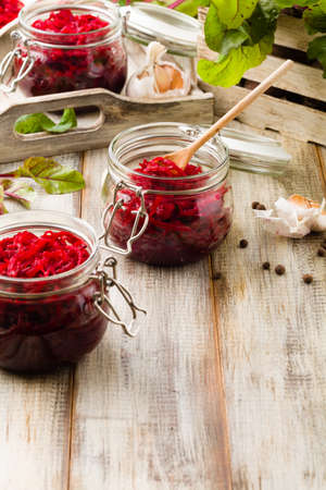 Grated beetroot marinated in jars. Wooden background.の写真素材