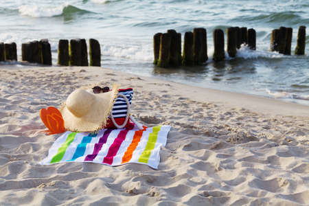 Beach bag with a towel, sunglasses, thongs and hat on the beach.の写真素材