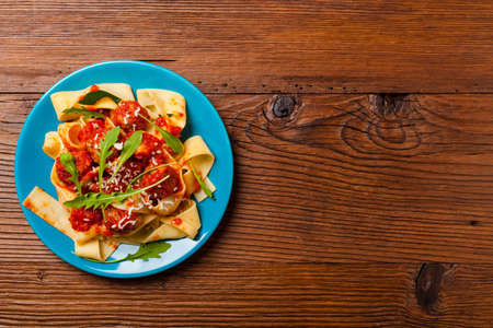 Italian pasta pappardelle with meatballs in tomato sauce, sprinkled with cheese and arugula. Top view.の写真素材