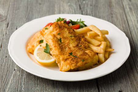 Fried cod with french fries on white plaet. 