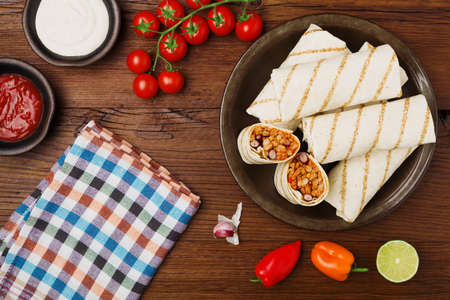 Burritos wraps with meat, beans and vegetables on wooden boardの写真素材