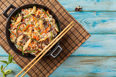 Rice noodles with chicken, mushrooms mun and vegetables, prepared in wook. Top view.の写真素材