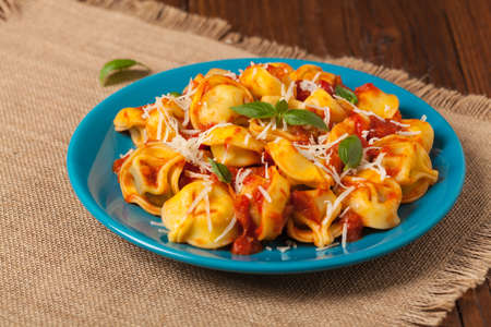 Delicious tortellini with meat in tomato sauce, sprinkled with parmesan cheese and basil. Front view.の写真素材