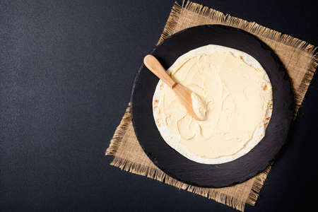 Tortilla with vegetables and hummus with chickpeas. Top view. Black background.