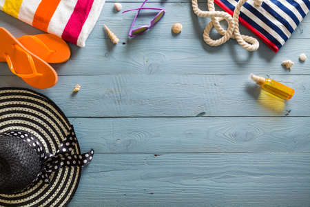 Summer vacation background theme with seashells, bag, hat, sunglasses and blue wood background with...