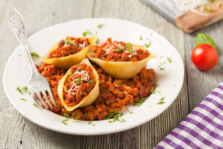 Italian pasta Conchiglioni Rigati stuffed with dry tomatoes and meat. Sprinkled with cheese. Front view.の写真素材